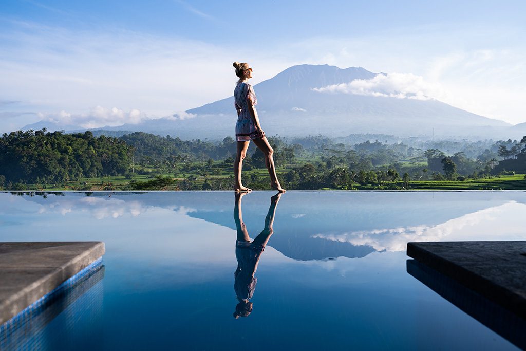 still water reflecting woman walking with mountain in the backgroundd