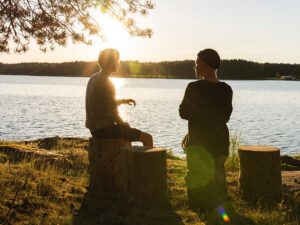 2 guys talking calm water sunset background