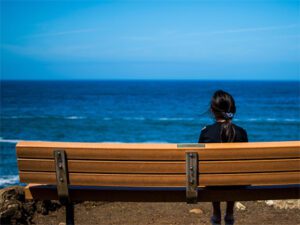 peacful deep relaxation seaside picture of woman sat on bench