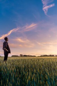 Man in quiet field aloone looking at sunset