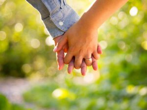 picture of 2 hands clasped in intimacy as they walk through a peaceful wood